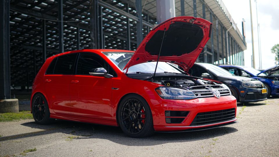 A red volkswagen golf gti with its hood open.